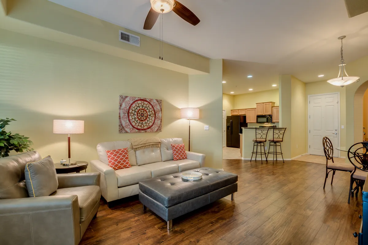An open-plan living space with a comfortable sofa, coffee table, tasteful wall art, and a clear sightline to the kitchen area. The ambiance is welcoming, ideal for both relaxation and casual dining.